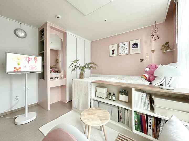 明るいホワイトとピンクの色調の子供部屋、ベッドと本棚が配置された居心地の良く整った空間