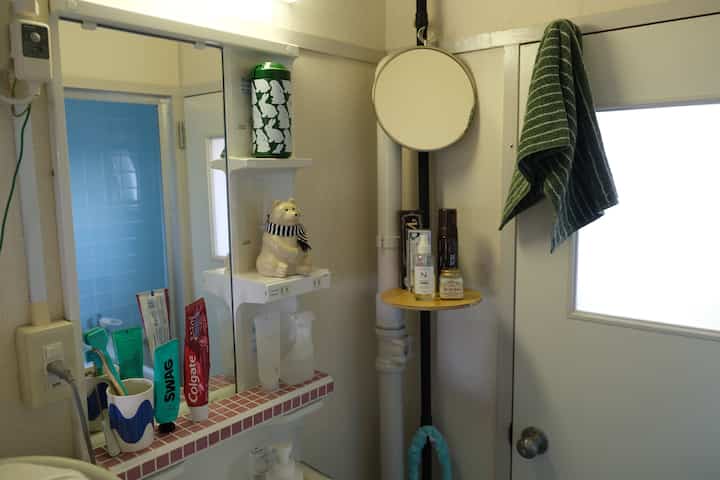 白を基調とした狭いお手洗い、鏡と収納アイデアが配置された印象的な空間