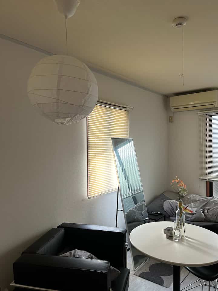 モノトーンのリビング、黒いアームチェアと白い円形テーブルに花瓶が置かれた、シンプルで落ち着いた雰囲気のインテリア