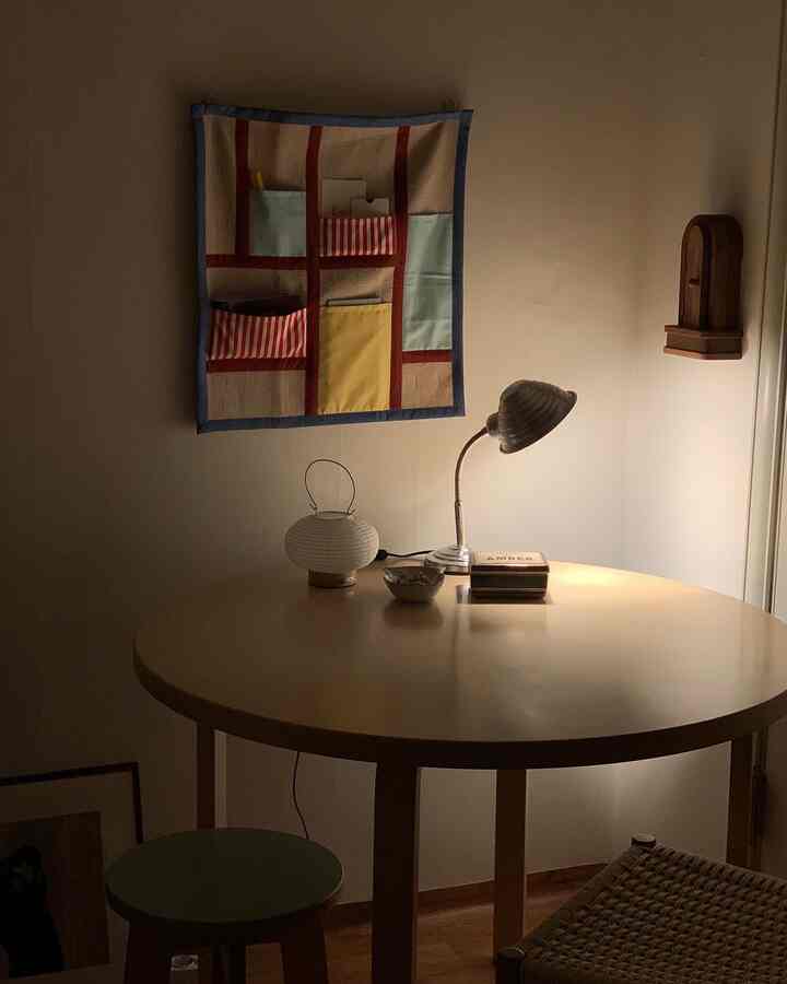 暖かいナチュラルカラーの約6畳のダイニング、丸いダイニングテーブルとテーブルランプが置かれたシンプルな空間