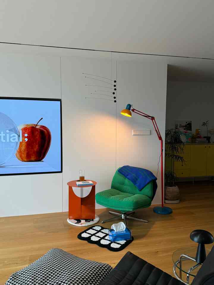 木目調の床と白い壁のあるミュージック兼フォトゾーン、緑のアームチェアとカラフルなスタンドランプが配置された落ち着いた空間