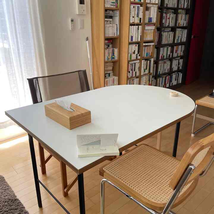 White and wood-toned living room featuring a dining table, chairs, and a bookshelf with a cozy atmosphere