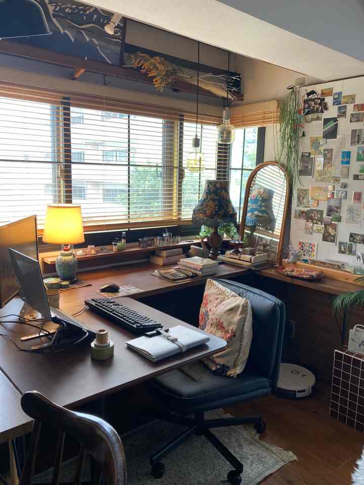 ブラウン系の温かみのあるワークスペース、大きなデスクとヴィンテージ照明が配置された自然な雰囲気のホームオフィス