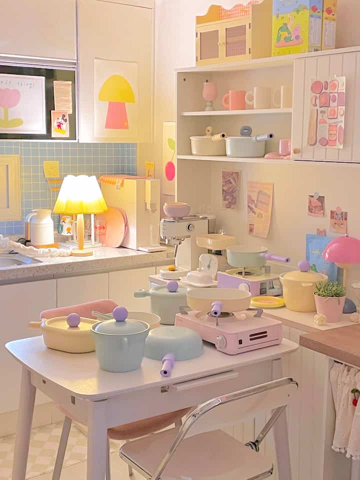 A pastel-toned cozy kitchen featuring colorful cookware and various cooking utensils arranged neatly.