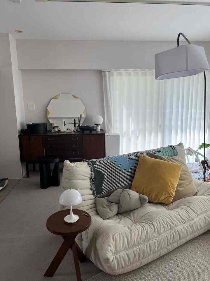 Natural beige-toned living room featuring modern sofa, round side table, table lamp, and floor lamp creating a cozy atmosphere