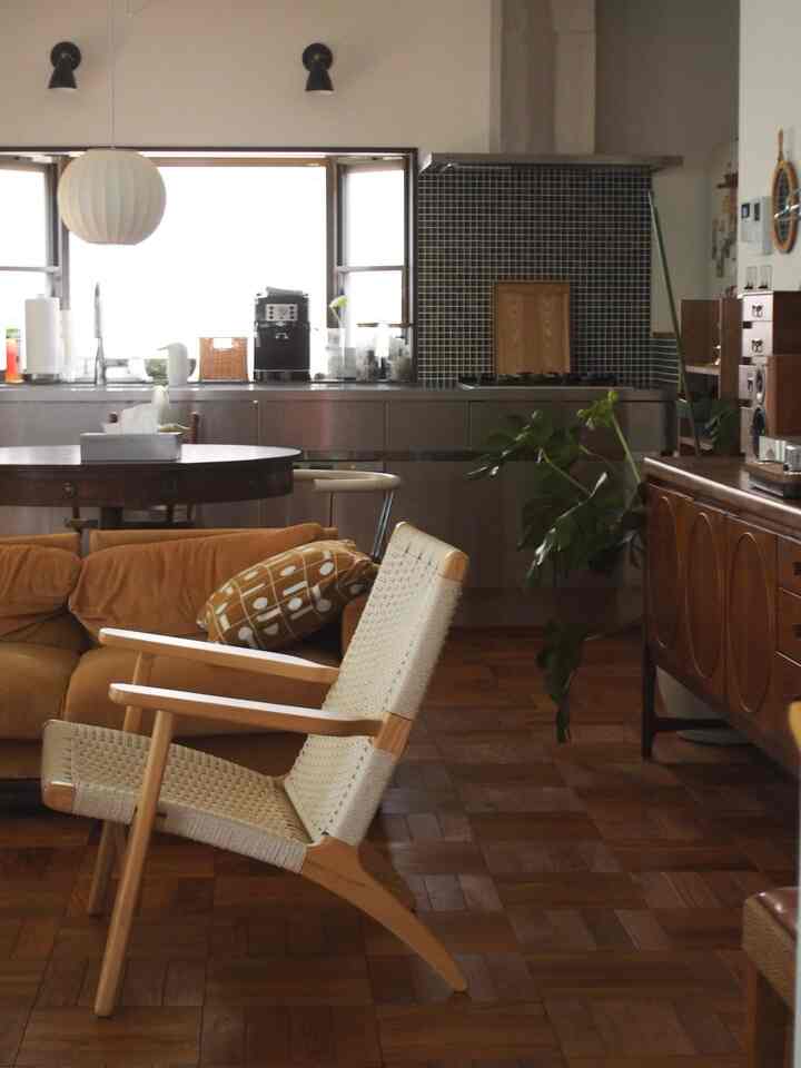 Warm yellow and brown wood tones blend in a living room with kitchen, featuring natural furniture and a plant for cozy atmosphere
