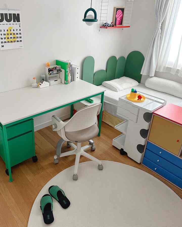 明るい白と緑の色調の子供部屋、子供用机とベッドが配置された清潔感のある空間