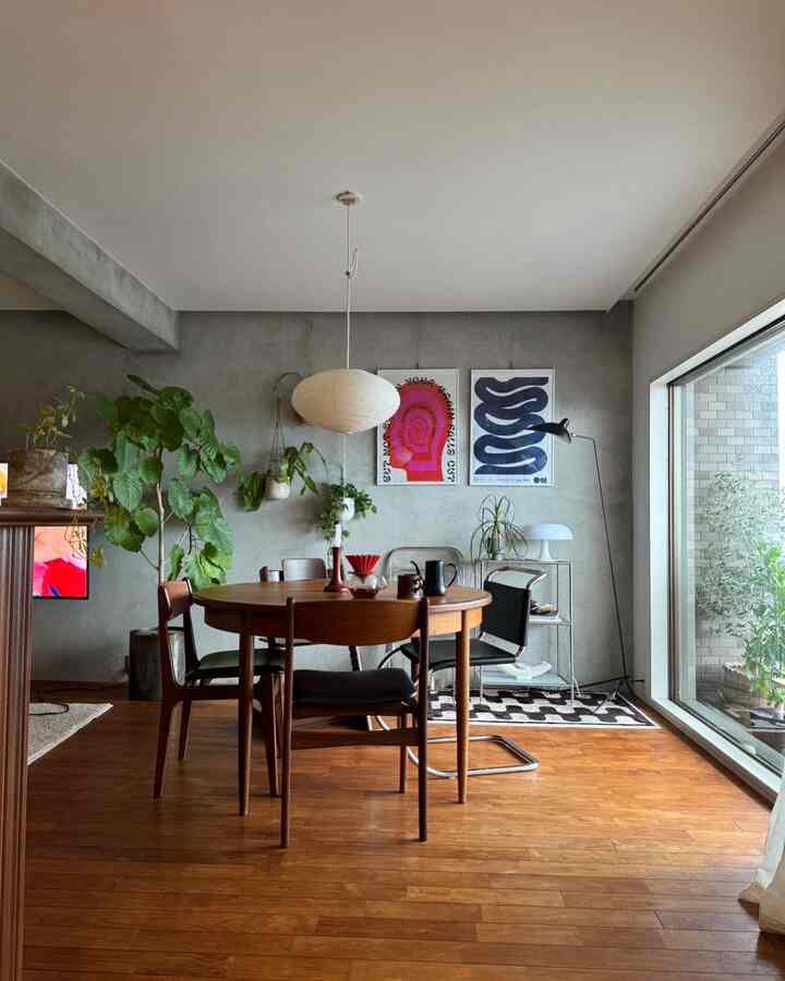 木目調とグレーの壁が調和するダイニングルーム、丸テーブルと植物が配置されたモダンなカフェ風の雰囲気のあるインテリア