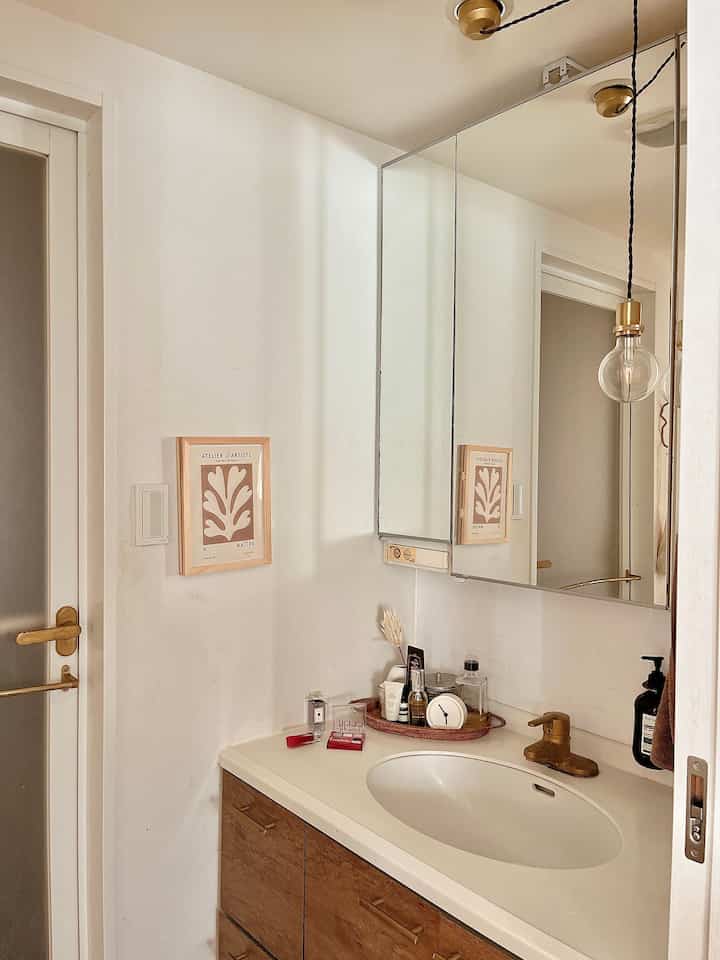 白と木目調が調和したバスルームの洗面台と鏡、自然で清潔感のある印象的なパウダールーム空間