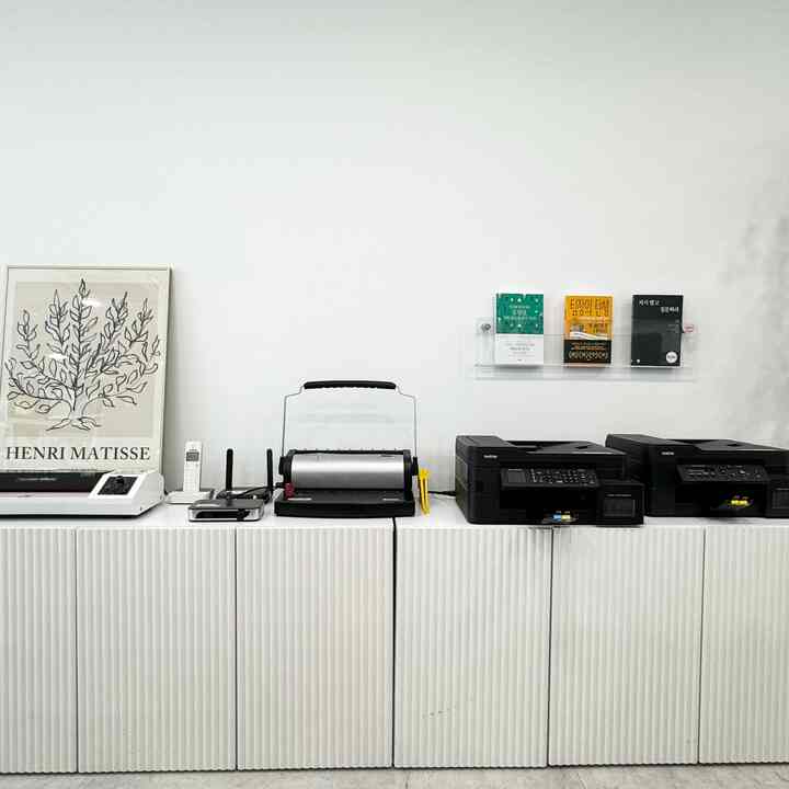 白を基調としたホームオフィス空間、低い収納棚の上にオフィス機器が整頓された印象的なインテリア