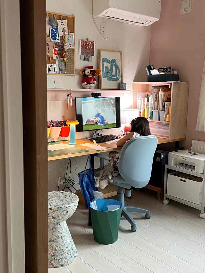 明るい白い壁とベージュの机、ブルーのオフィスチェアが配置された子供部屋のホームオフィス空間