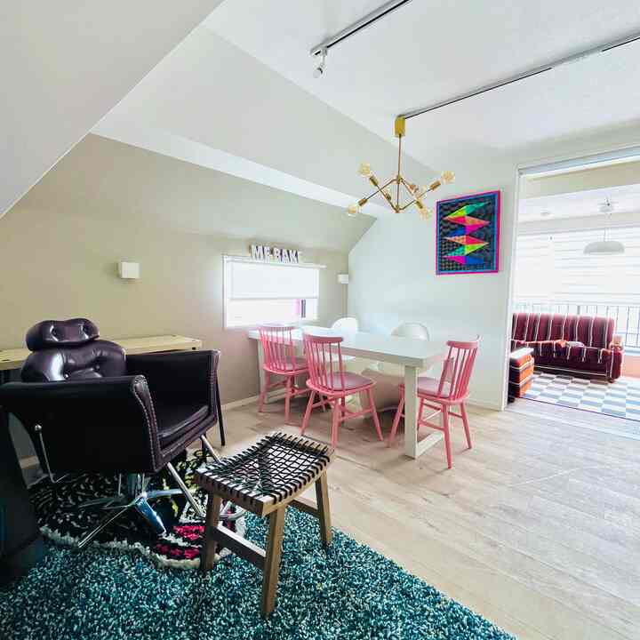 白とピンクのトーンのダイニングルームとリビングがつながる空間、アールデコスタイルの照明が中心に配置された明るく整ったインテリア