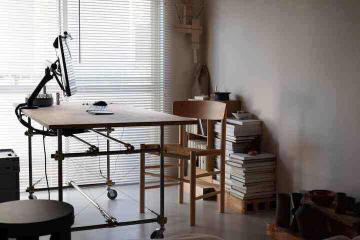 Natural-toned home office space featuring wooden desk and chair with neatly stacked books in a modern setting