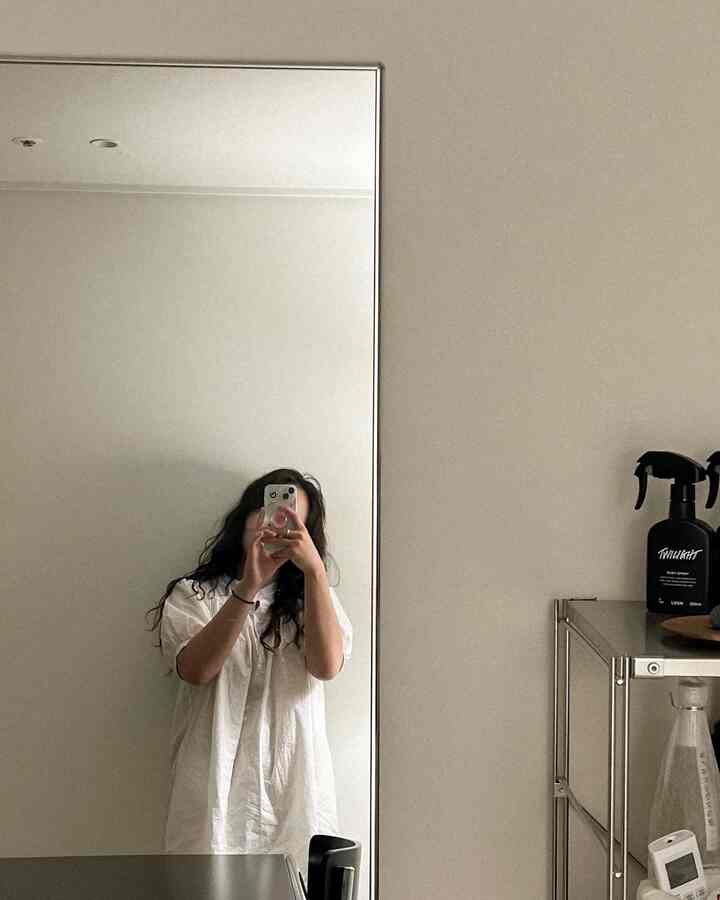 ライトグレーの色調のウォークインクローゼット兼ホームギャラリー、 大型の鏡とメタル棚が配置されたミニマルなインテリア