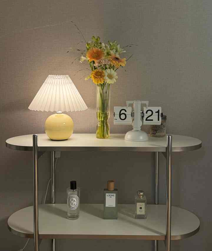 白と黄色のトーンで統一されたリビングのシンプルなテーブルにランプ、時計、花瓶が配置された落ち着いた空間