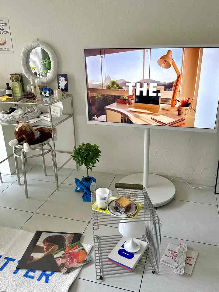 シルバーとホワイトの色調のリビング、ステンレスラウンドスツールと大型テレビが配置されたモダンなインテリア空間