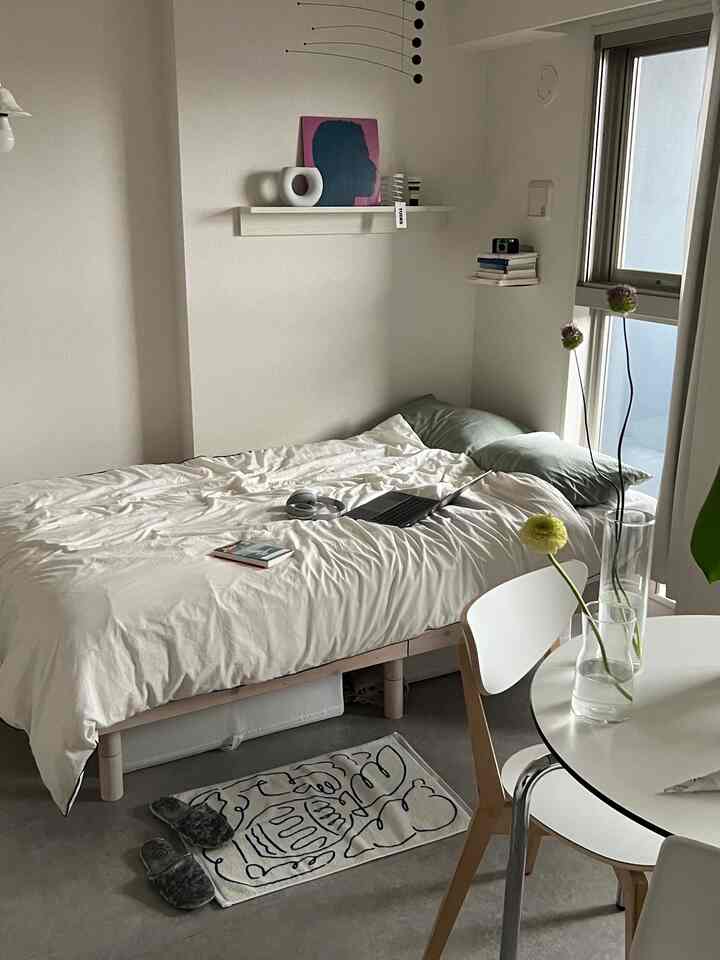 白と緑のトーンの寝室、ベッドと丸テーブル、植物が配置されたシンプルで自然な雰囲気のインテリア