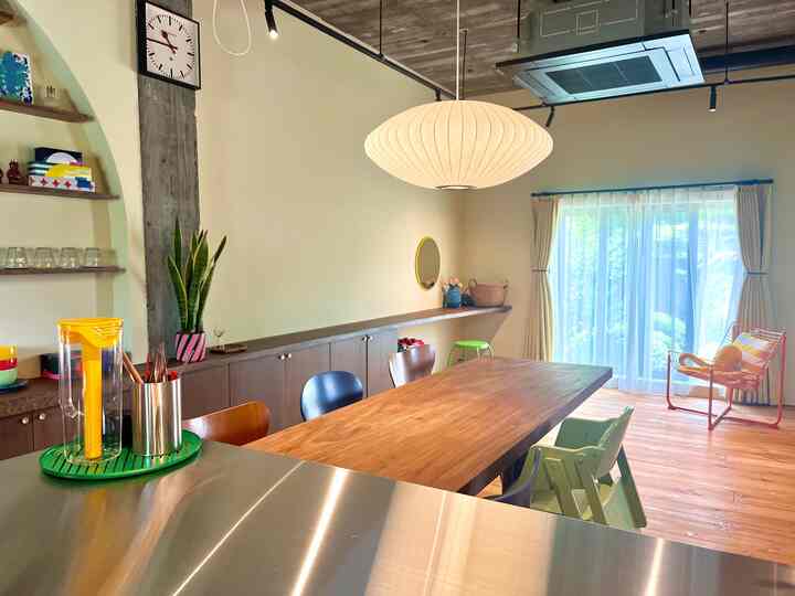 ウッドトーンとイエローのアクセントが調和するミッドセンチュリーモダンのダイニング、中央に大きなペンダントライトが配置された印象的な空間