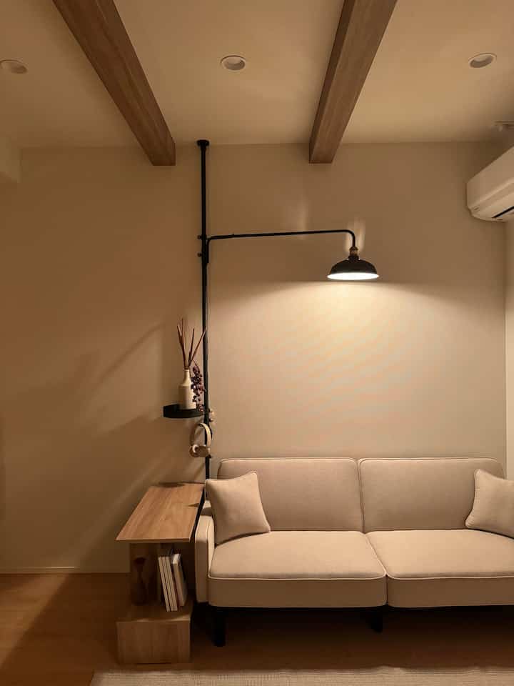 暖かいベージュと木目調のリビング、シンプルなベージュのソファと木製サイドテーブルが配置されたモダンでナチュラルな空間