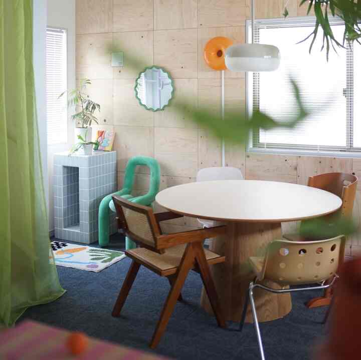 Natural color, blue, and green toned dining room featuring a round dining table with varied chairs in a bright, cozy setting