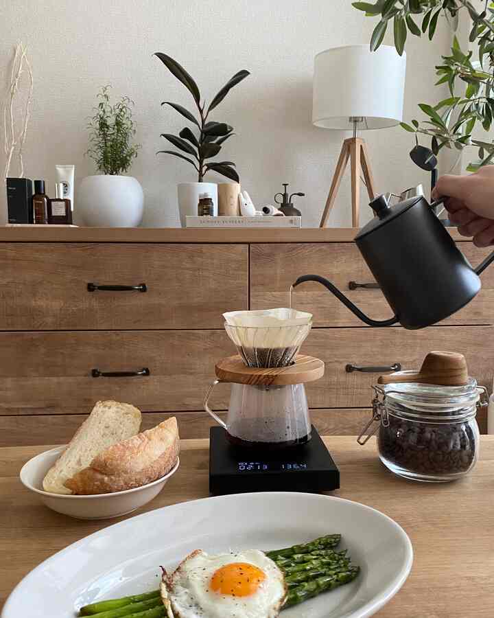 ナチュラルな木目調の空間、木製ダイニングテーブルにドリップコーヒーセットと朝食が置かれた温かみのあるインテリア