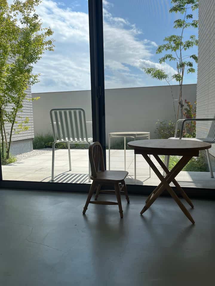 ナチュラルなトーンの中庭空間、木製の子供用テーブルと椅子が配置された明るく静かな室内外の雰囲気