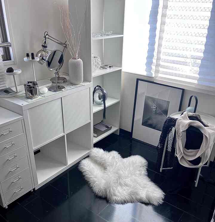 Monotone walk-in closet with white storage units, black flooring, and displayed accessories including a poster, creating a simple aesthetic