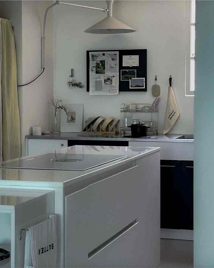 Modern kitchen in white and navy tones featuring a central kitchen island with storage racks and lighting on the walls in a clean setting