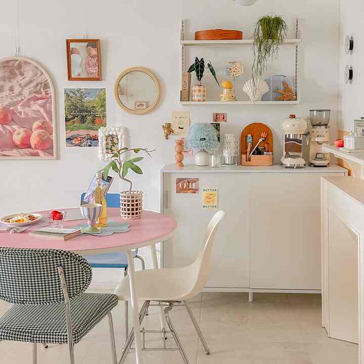 Dining room with pink table and white storage cabinet featuring Smeg coffee machine and baby photo, creating a cozy home cafe atmosphere