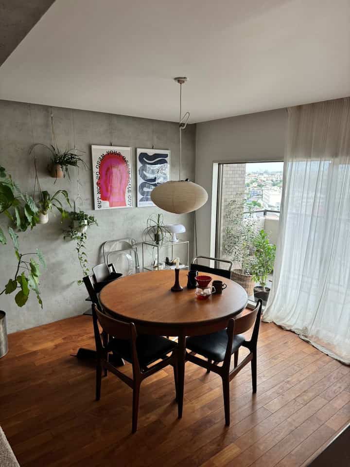 ウッドトーンとナチュラルな植物が配置されたミッドセンチュリーモダンのダイニング、丸テーブルとペンダントライトで温かな雰囲気のあるインテリア