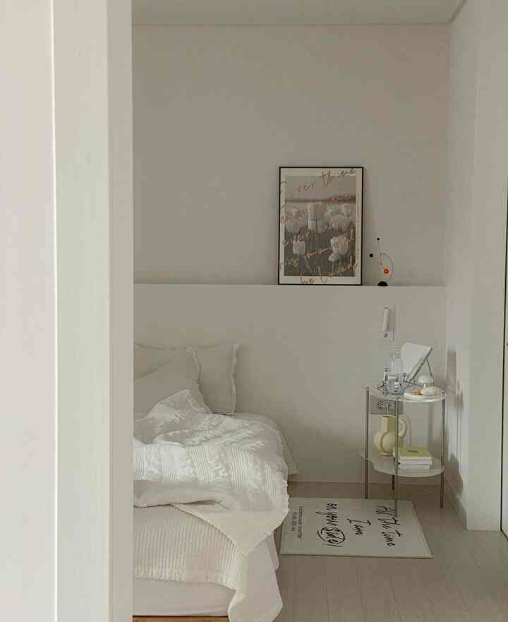 White-toned bedroom featuring a bed with white bedding and a nightstand, creating a simple and modern space
