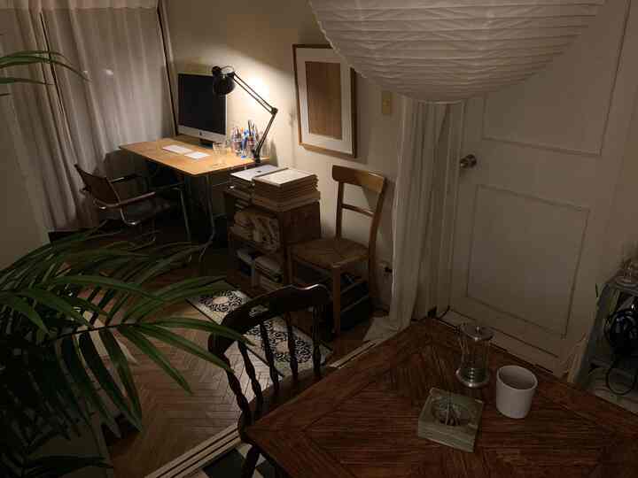 木目調のナチュラルな色合いのアパートのホームオフィス空間、デスクとダイニングテーブルが配置された雰囲気のあるインテリア