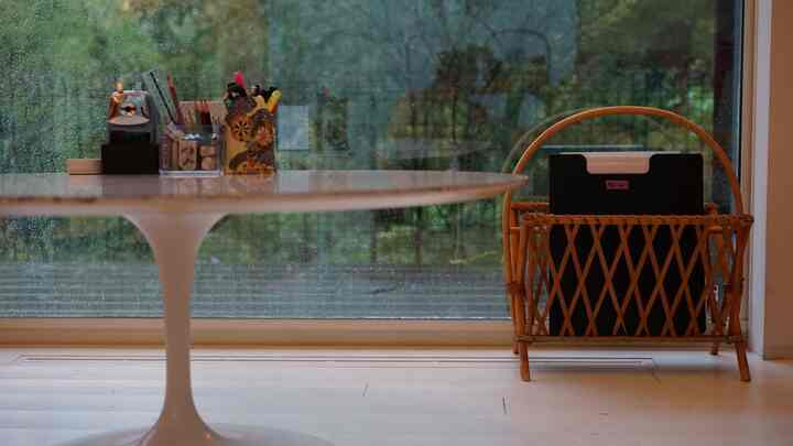A white and brown toned living room featuring a rattan magazine rack and round table with a natural and tidy atmosphere