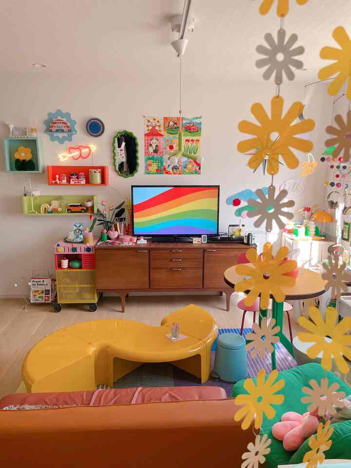 明るい黄色と緑を基調としたリビング、ミッドセンチュリーモダン家具とカラフルなレトロ装飾が印象的な空間
