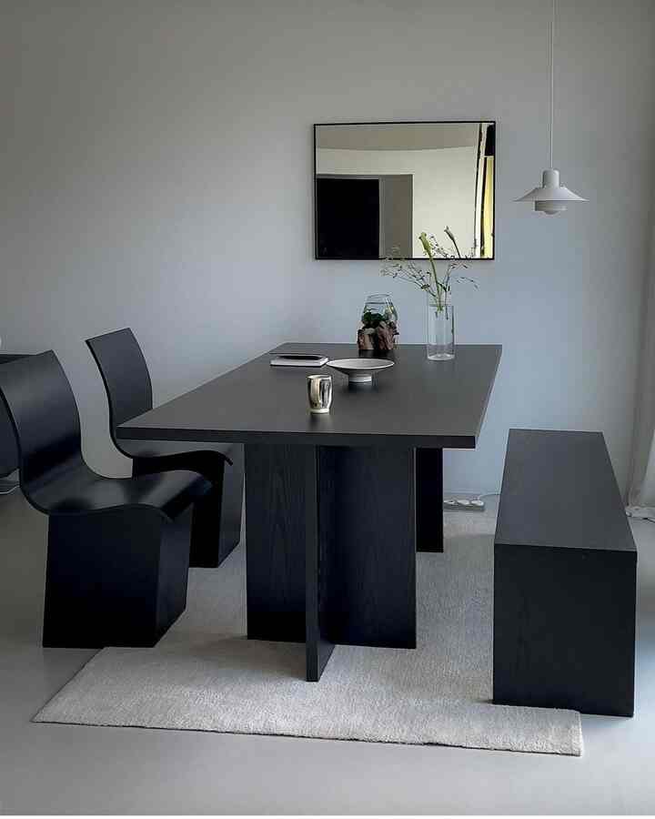 黒と白のトーンでまとめられたミニマルなリビング、黒いダイニングテーブルとチェア、ベンチが配置された印象的な空間