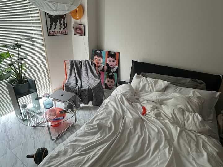 Monotone-tone 1K bedroom featuring a large bed, orange armchair, and stylish wall art with a clean atmosphere