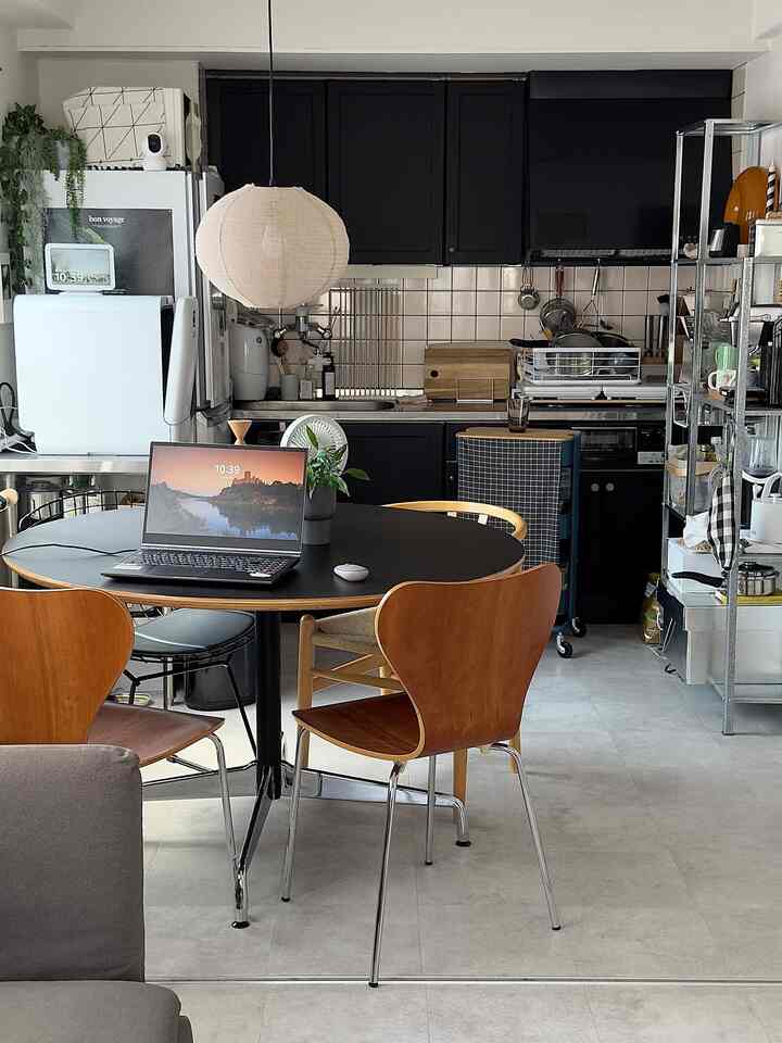 黒と茶色のトーンのダイニングルームとキッチン、ノートパソコンと収納キャビネットが配置されたモダンで実用的なインテリア