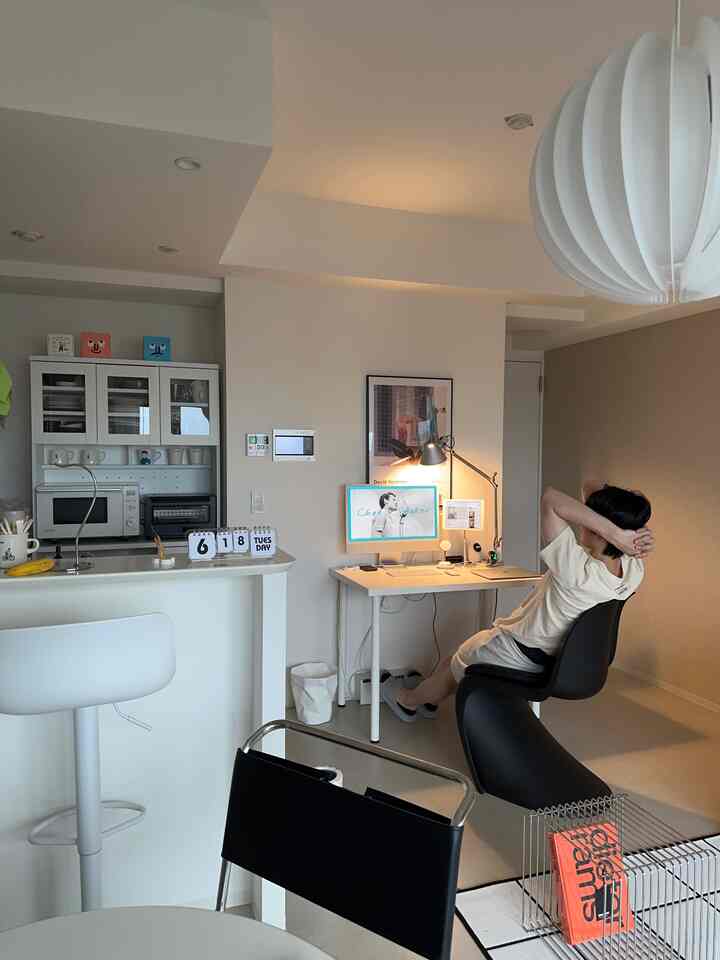 Modern living room in white and black tones featuring a white desk and black Panton chair in a remote work home office setup