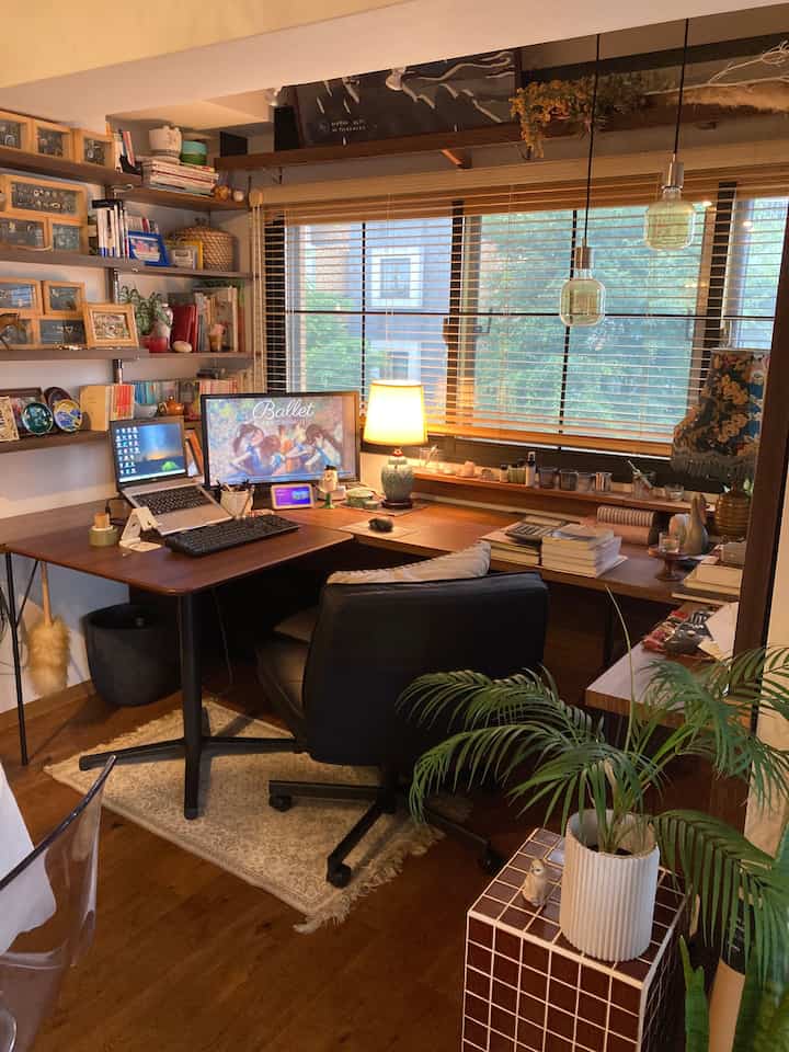 Brown wood tone compact workspace featuring L-shaped desk and office chair by a window, creating a cozy home office atmosphere