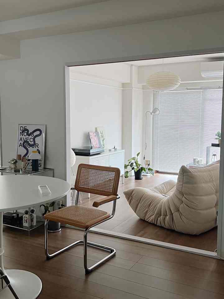 Beige and white toned compact studio living room featuring simple furniture and pendant light with warm atmosphere