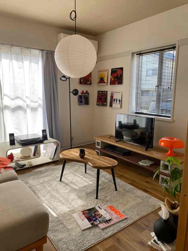 ホワイトと木目調のリビング、中央に楕円形のコーヒーテーブルとベージュのソファが配置された落ち着いた空間