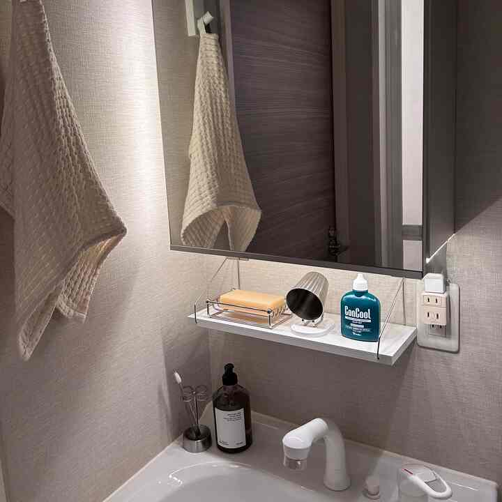 アイボリーのタオルと白い洗面台、大きな鏡が配置されたモダンなバスルーム空間