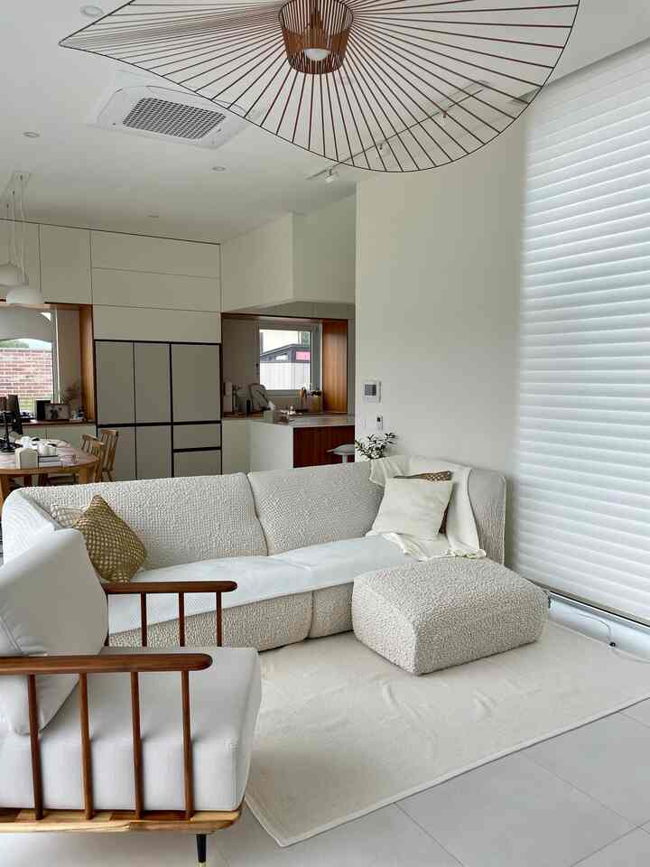Bright and modern living room featuring a natural wood armchair, white sofa, and rug