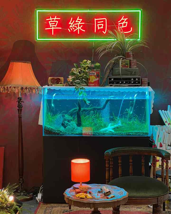 深い赤と黒のトーンのレトロな空間、大きな水槽とヴィンテージ照明が配置された雰囲気のあるホームカフェ