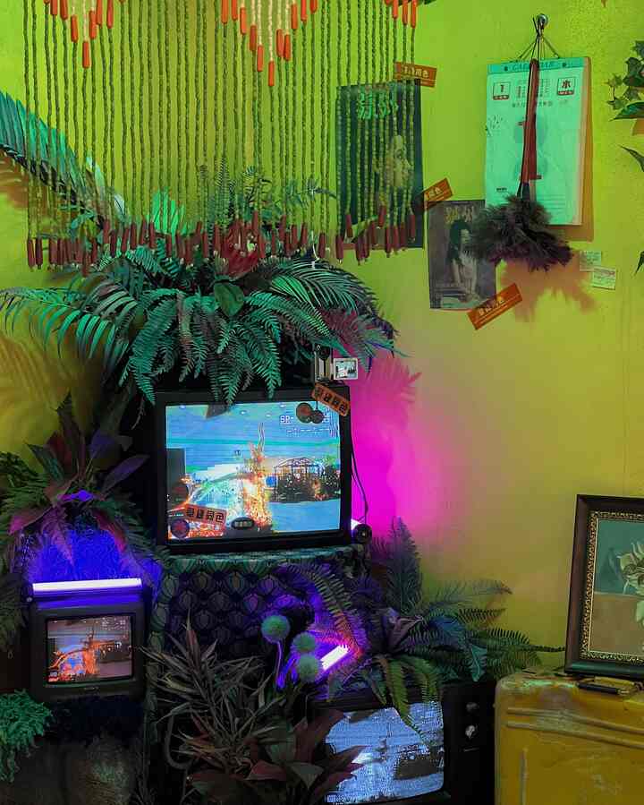 黄色い壁と緑の植物が配置されたレトロでインスタ映えする空間、ヴィンテージテレビとカラフルな照明が雰囲気のあるインテリアを演出している