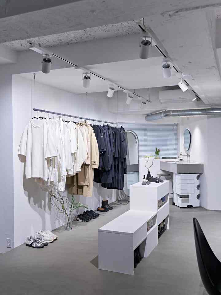Monotone walk-in closet featuring ceiling spotlights, DIY shoe cabinet bench, and minimalist inorganic interior with dominant white tones