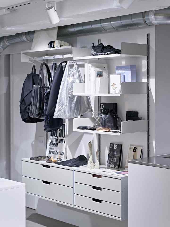 Minimalist entrance storage space in white and gray tones featuring 606 Universal Shelving System shelves and cabinets