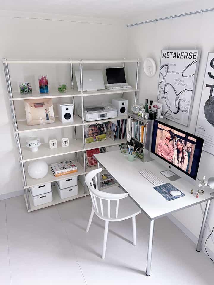 White tone compact home office featuring desk, bookshelf, and modern framed posters in a clean work environment