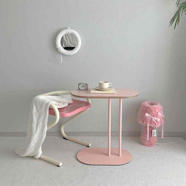 A small room in pink and white tones featuring a pink side table and armchair with a simple, minimal atmosphere