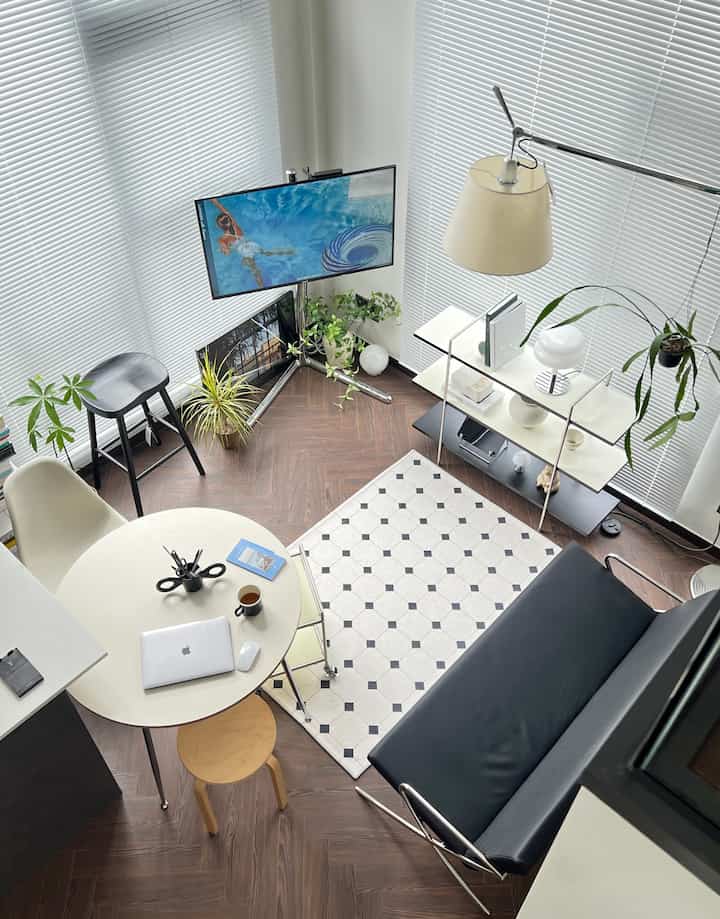 White and brown toned living room featuring round table, black sofa, and minimalist modern design